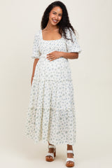 woman wearing a floral print maternity maxi dress with puff sleeves and a visible baby bump