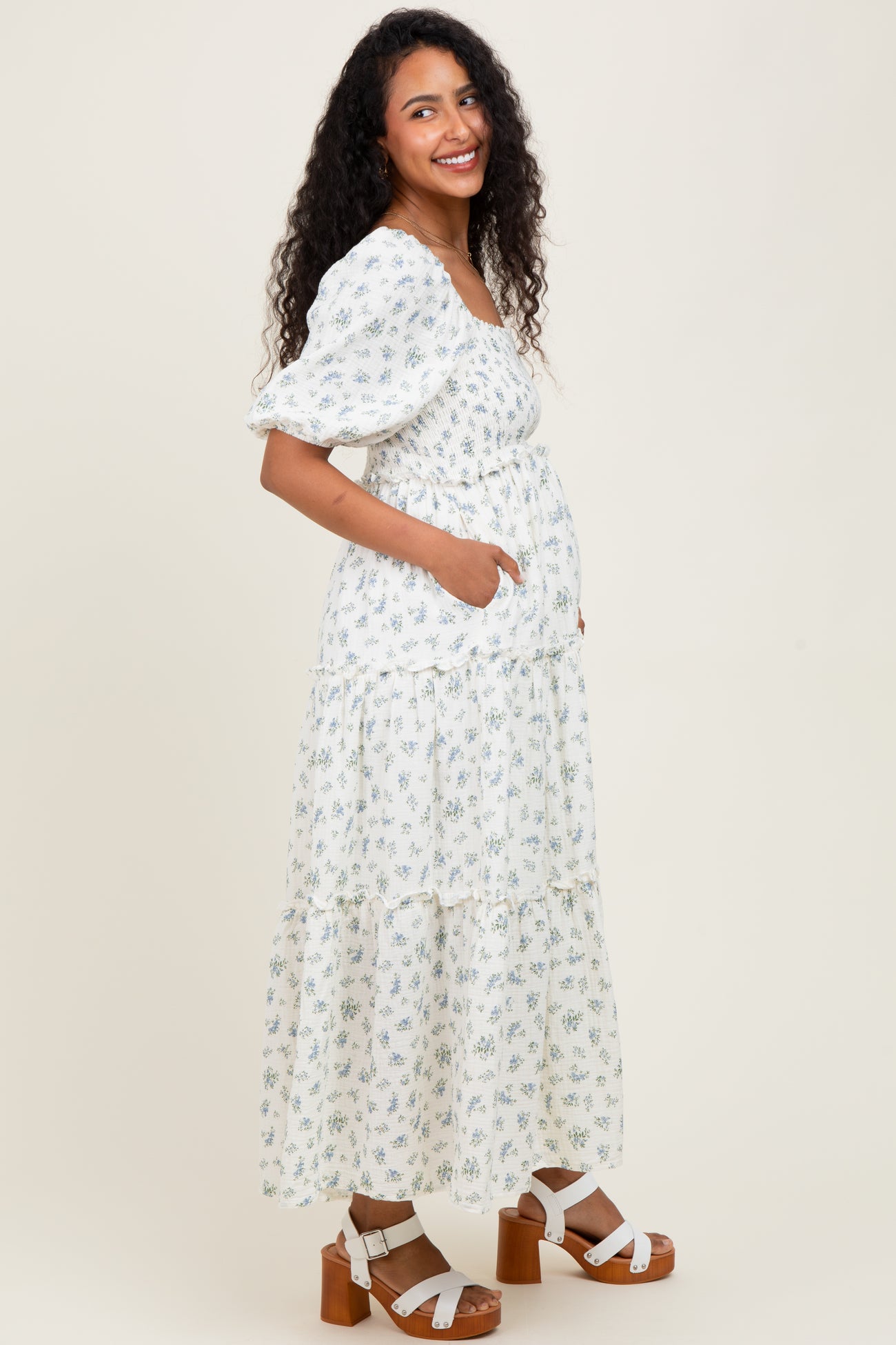 woman wearing a white floral maternity maxi dress with puff sleeves and a baby bump