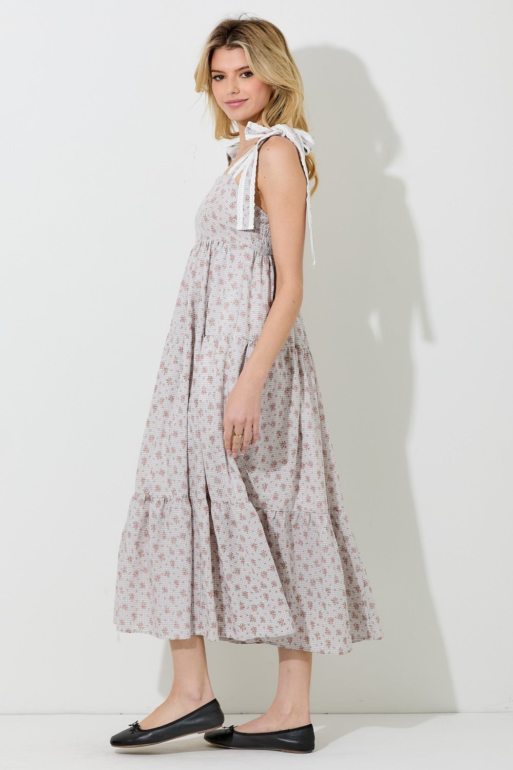 woman wearing a light pink floral maxi dress with tie straps and a tiered skirt