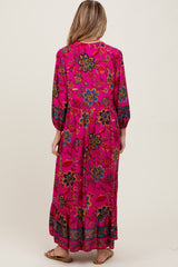 woman wearing a bright pink floral maternity maxi dress with long sleeves and a flowing skirt