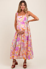 woman wearing a floral maternity maxi dress with spaghetti straps and holding her baby bump