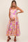 woman wearing a floral maternity maxi dress with spaghetti straps and holding her baby bump
