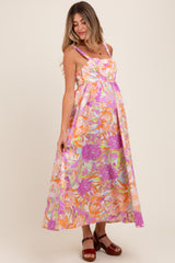 woman wearing a colorful floral print maternity maxi dress with spaghetti straps and a visible baby bump