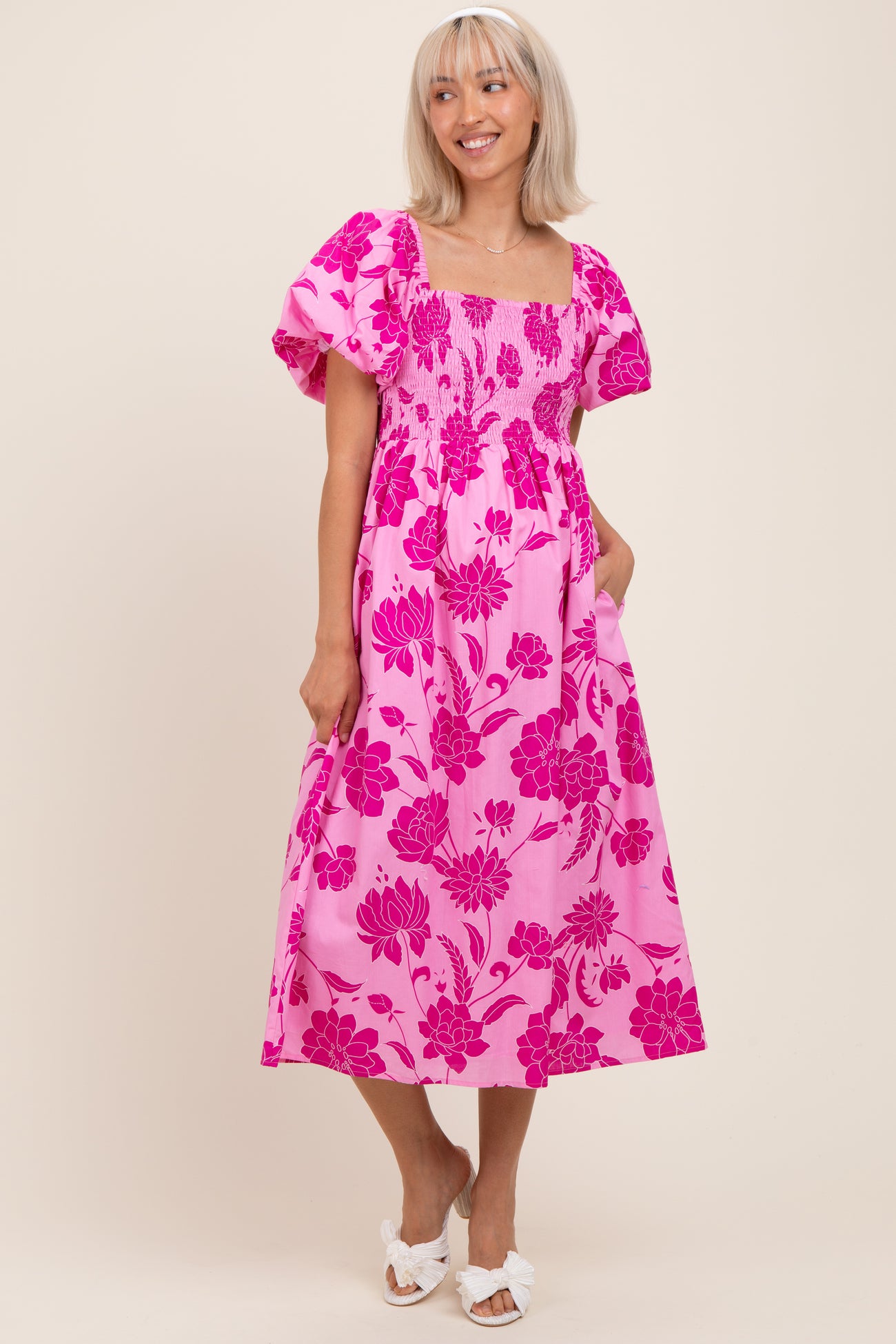 woman wearing a pink floral maternity dress with puff sleeves and pockets