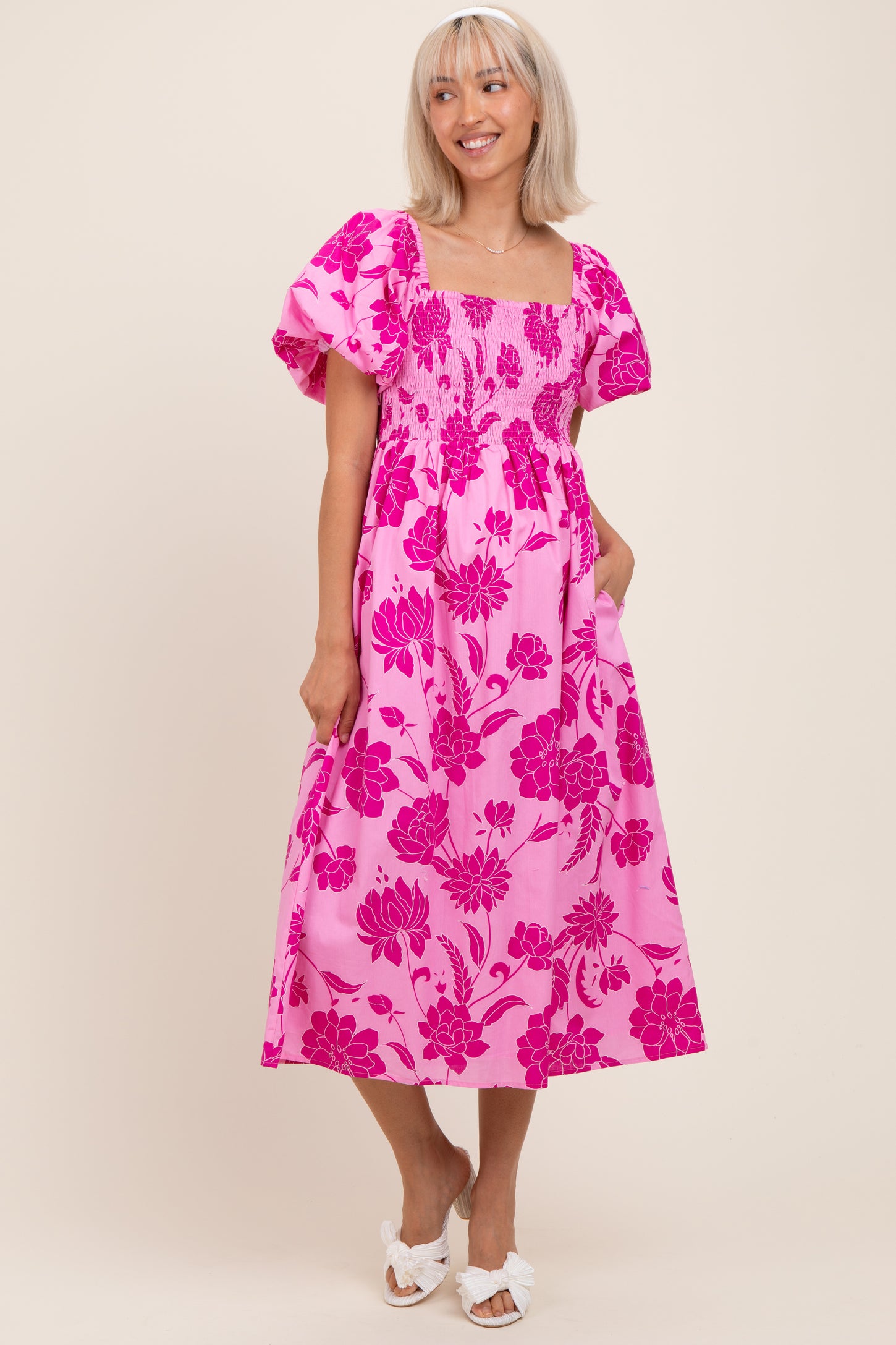 woman wearing a pink floral maternity dress with puff sleeves and pockets