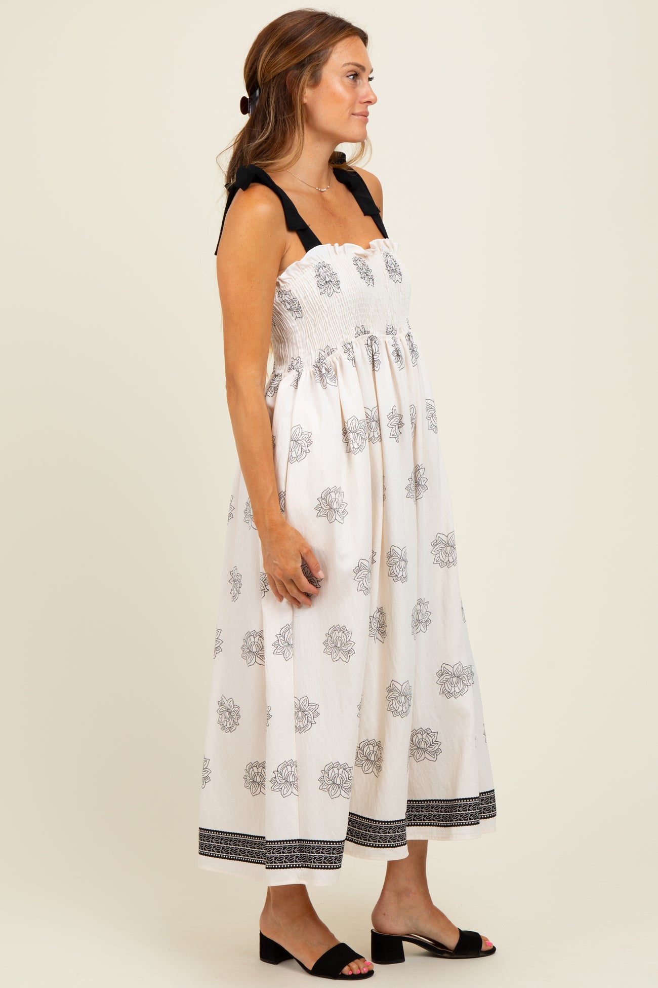 woman wearing a white floral print maxi dress with black straps and a smocked bodice