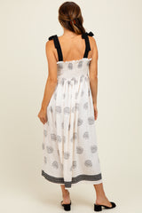 woman wearing a white floral print midi dress with black straps and smocked back details