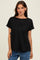 woman wearing a black short sleeve ribbed top with a relaxed fit, standing in front of a neutral background