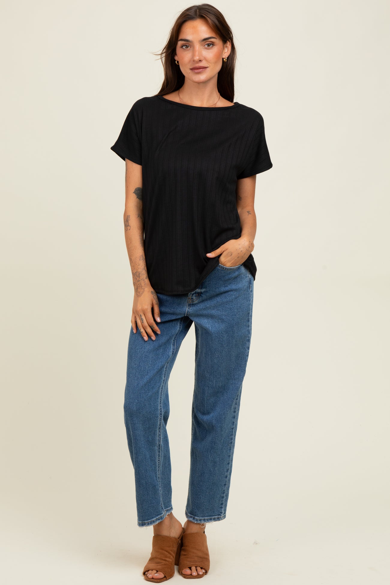 woman wearing a black ribbed short sleeve top with a relaxed fit and blue high-waisted straight leg jeans