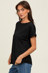 woman wearing a black short sleeve top with a textured ribbed design and relaxed fit