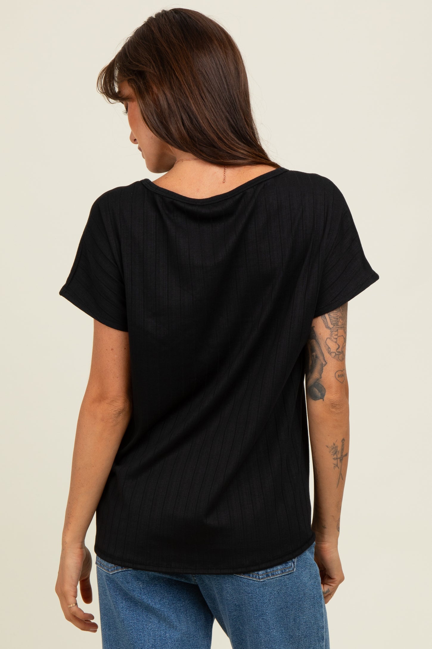 woman wearing a black short sleeve top with a ribbed texture and relaxed fit, viewed from the back