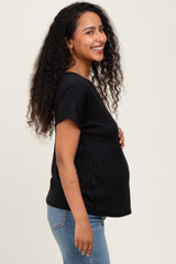 woman wearing a black ribbed maternity top and showing her baby bump, paired with blue jeans