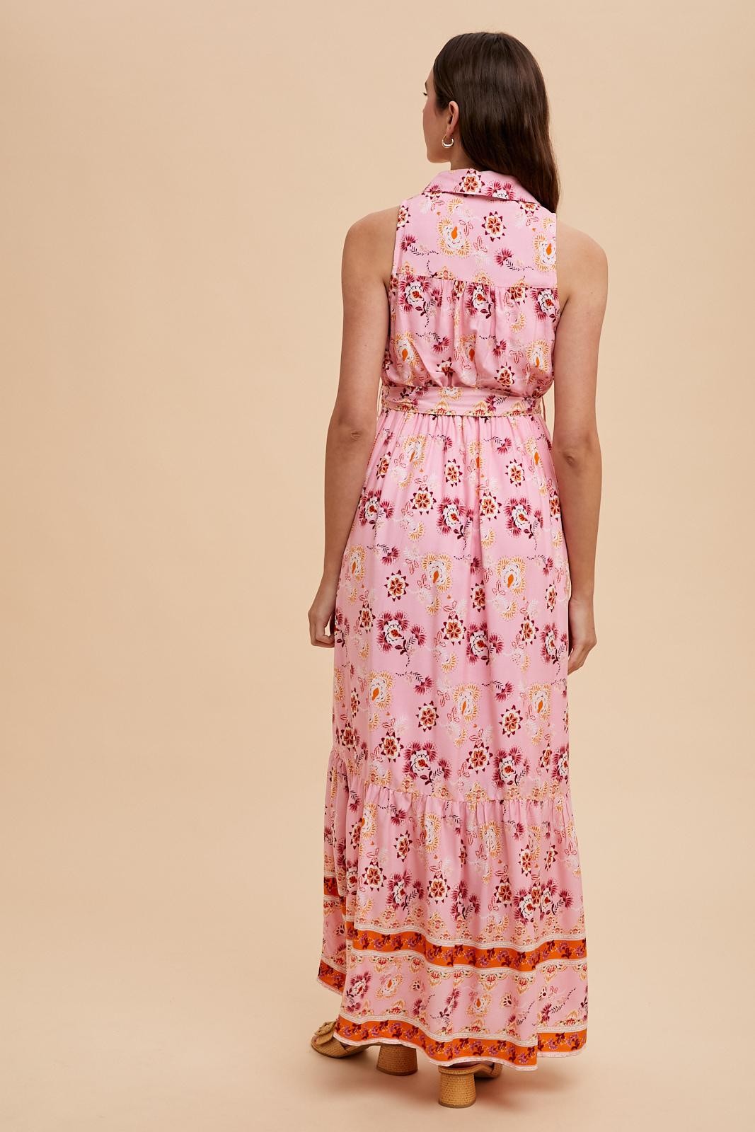 woman wearing a pink floral maxi dress with a tiered skirt and a belted waist, seen from the back