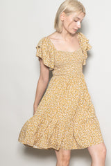 woman wearing a yellow floral print dress with ruffled sleeves and a fitted bodice