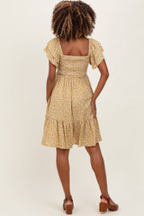 woman wearing a yellow floral maternity dress with flutter sleeves and a smocked back, shown from the rear