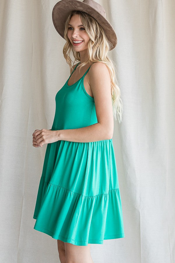 woman wearing a vibrant green sleeveless tiered sundress and a wide-brimmed hat
