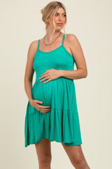 woman wearing a teal maternity dress with a fitted top and tiered hem, holding her baby bump