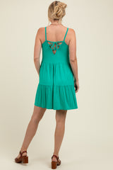 woman wearing a green maternity sundress with a tiered skirt and crisscross back detail
