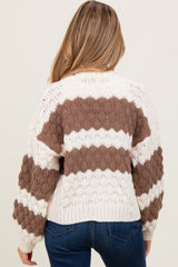 woman wearing a cream and brown striped oversized maternity sweater, with a loose fit and balloon sleeves