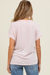 woman wearing a blush striped maternity top with rolled sleeves, viewed from the back, paired with light blue denim jeans