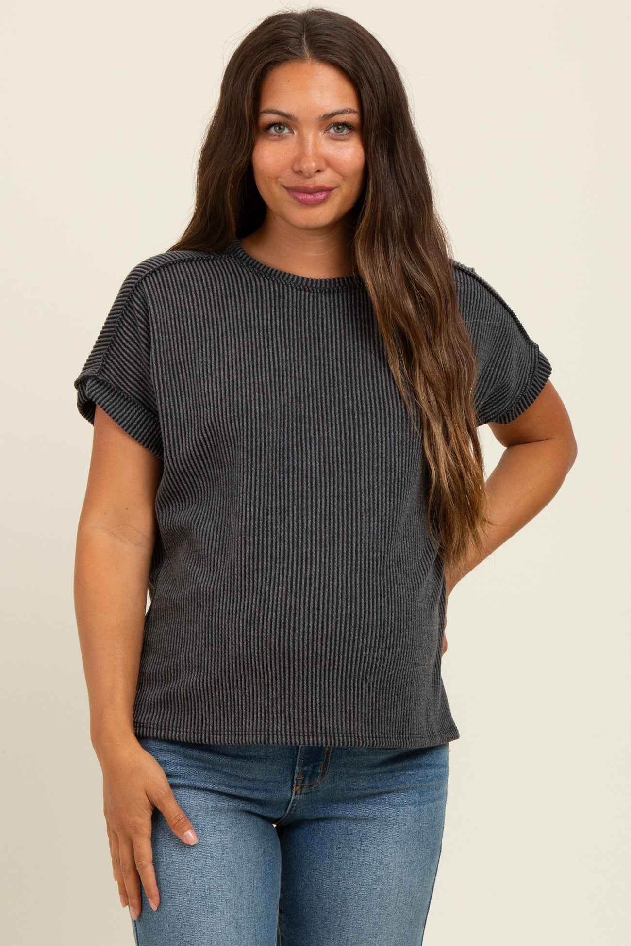 woman wearing a dark gray striped maternity top with rolled sleeves and a visible baby bump