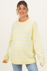 woman wearing a light yellow and white striped maternity sweater with a relaxed fit and round neckline