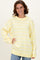 woman wearing a yellow and white striped oversized sweater with a ribbed neckline and long sleeves