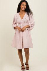 woman wearing a pink and white striped short dress with a deep v-neck and puff sleeves