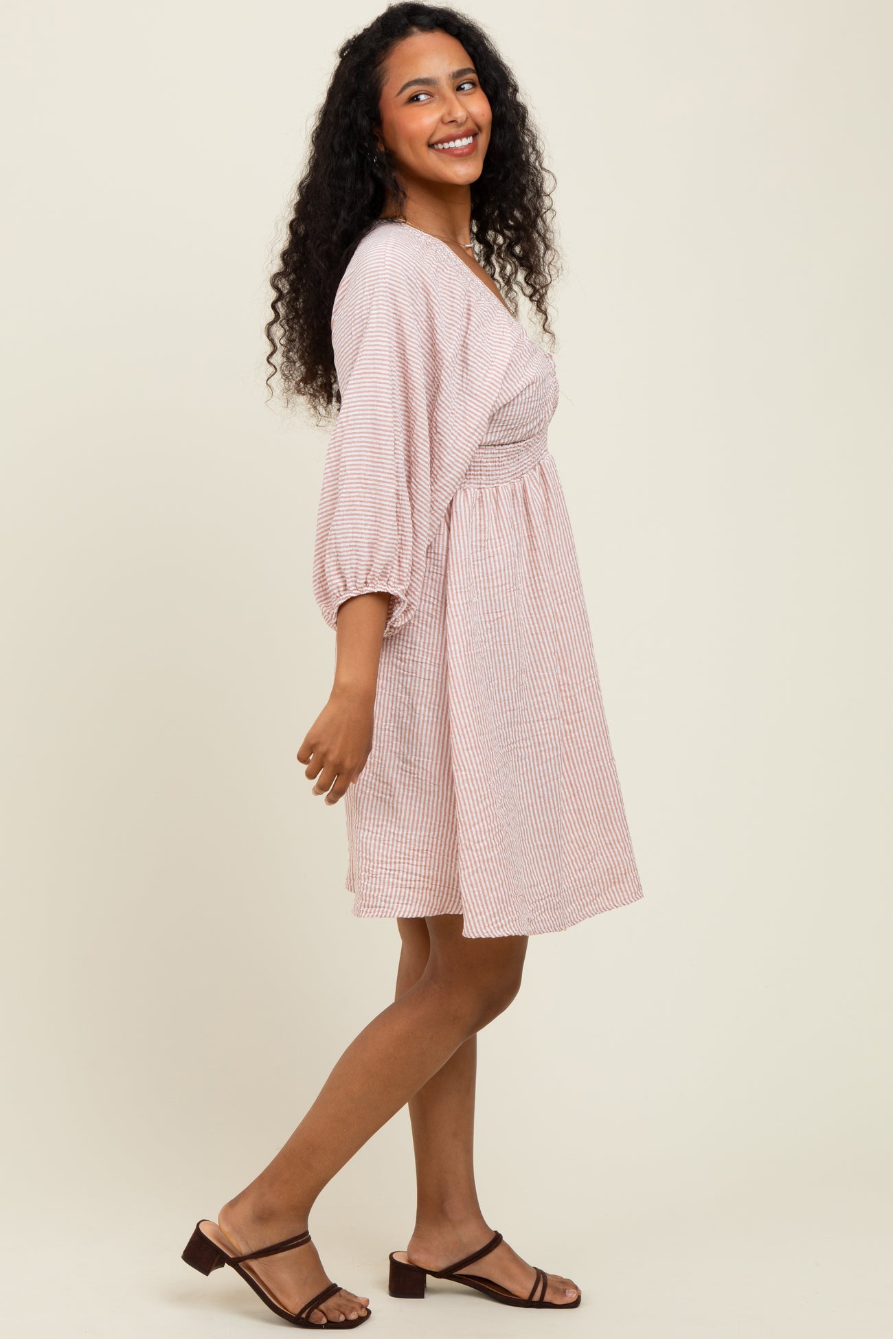 woman wearing a striped short sleeve dress with a fitted bodice and a flared skirt, smiling and standing sideways