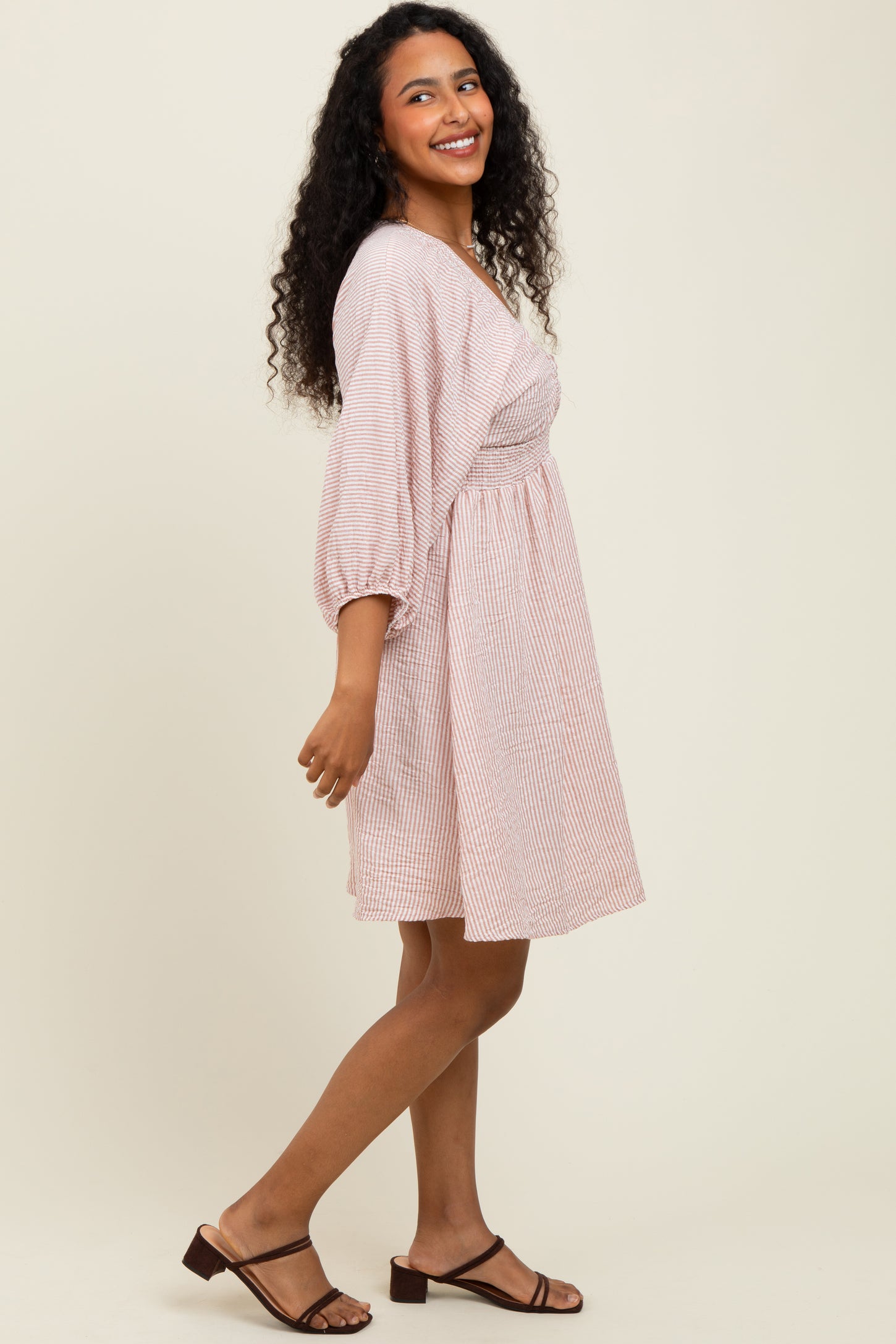 woman wearing a striped short sleeve dress with a fitted bodice and a flared skirt, smiling and standing sideways