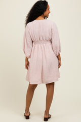 woman wearing a pink and white striped short sleeve dress with a smocked waist and balloon sleeves, shown from the back