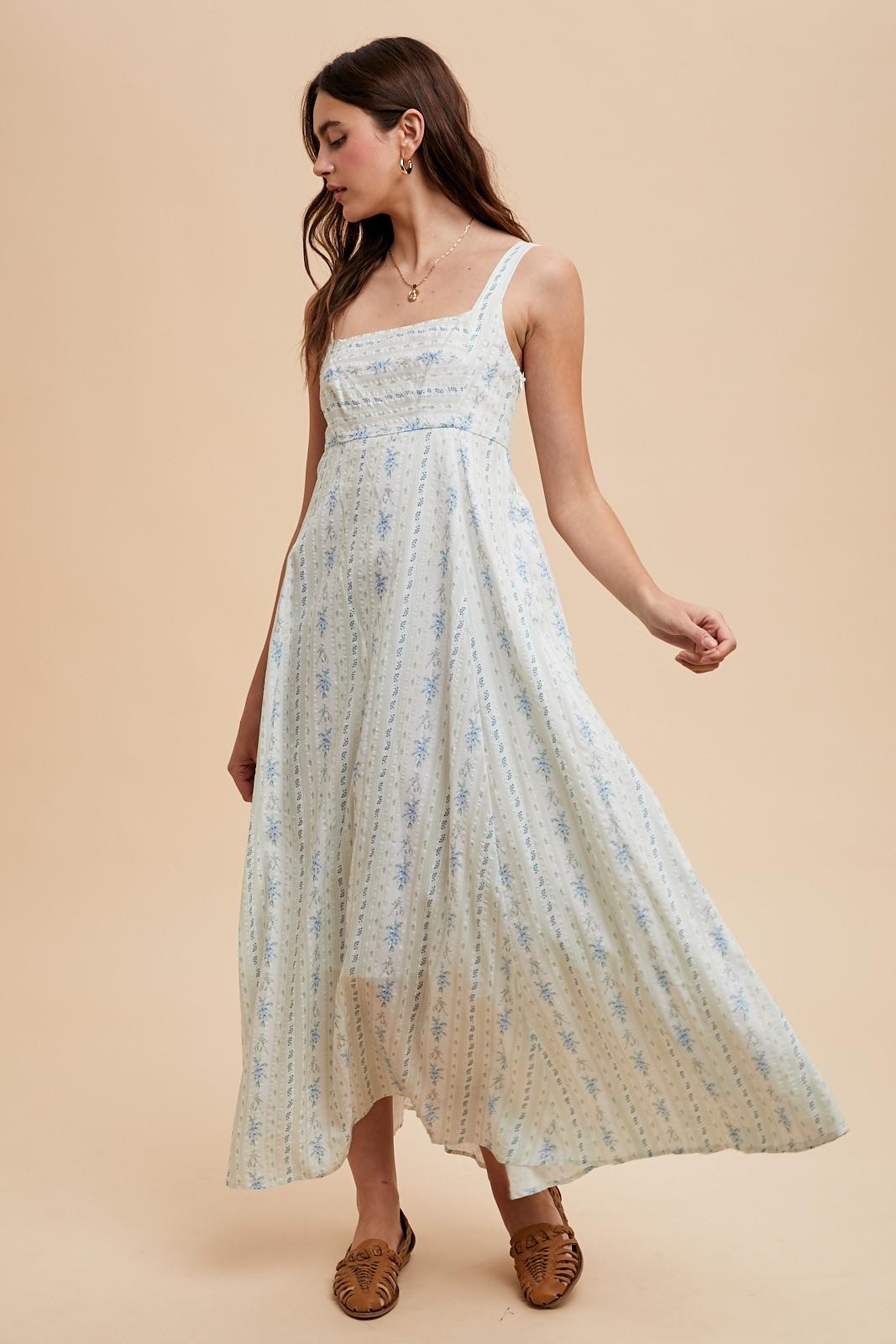 woman wearing a light blue floral maxi dress with spaghetti straps and a flowy silhouette
