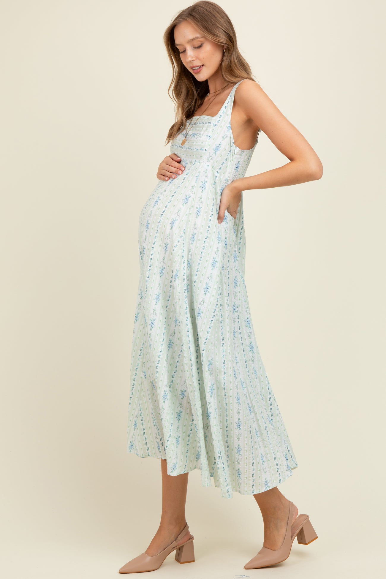 woman wearing a light blue floral maternity dress with spaghetti straps and baby bump visible