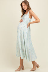 woman wearing a light blue floral maternity dress with spaghetti straps and baby bump visible