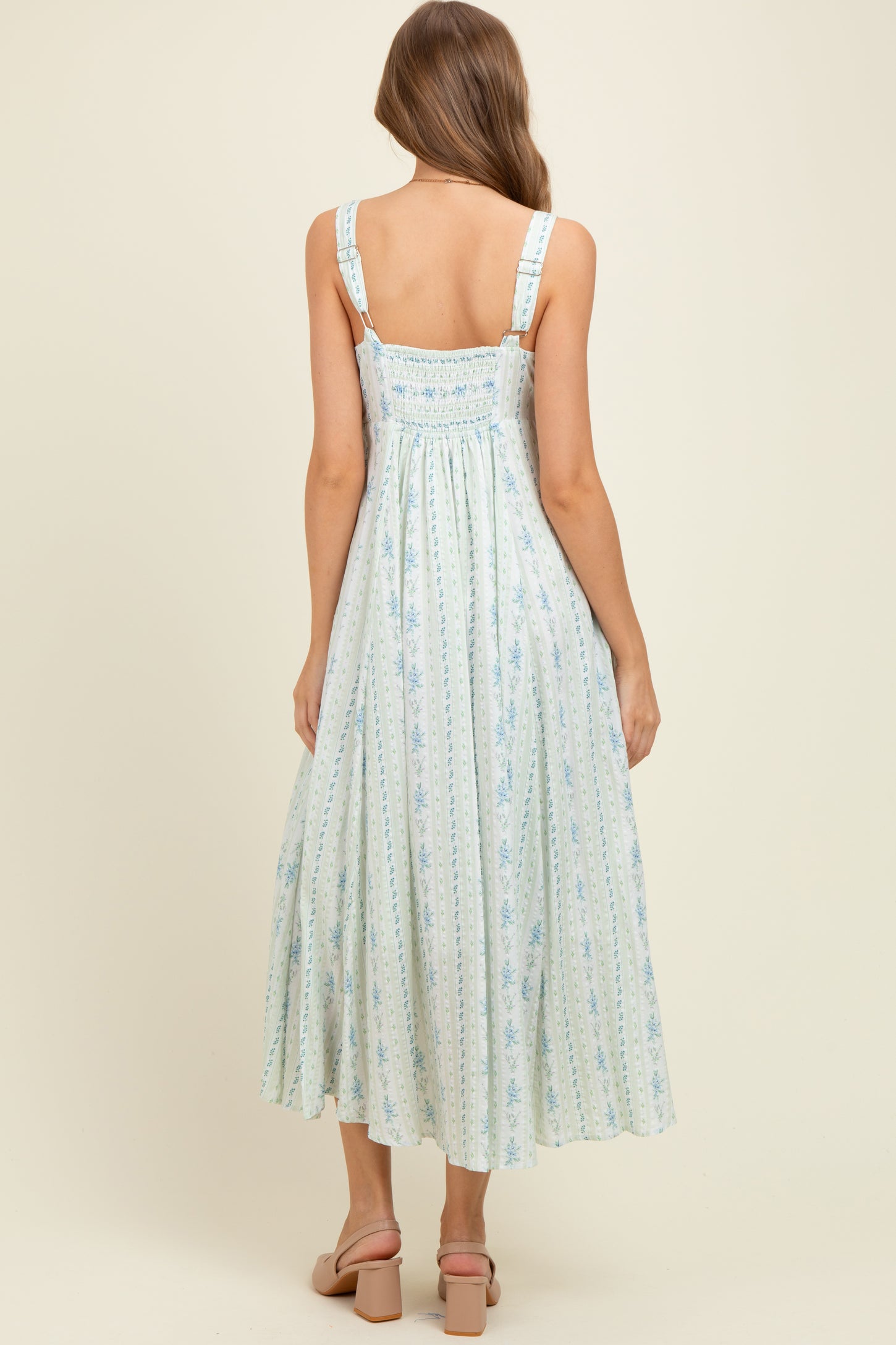 woman wearing a light blue floral print maternity maxi dress with adjustable straps and smocked back detail