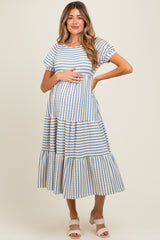 woman wearing a striped maternity maxi dress with short sleeves and a tiered skirt, holding her baby bump