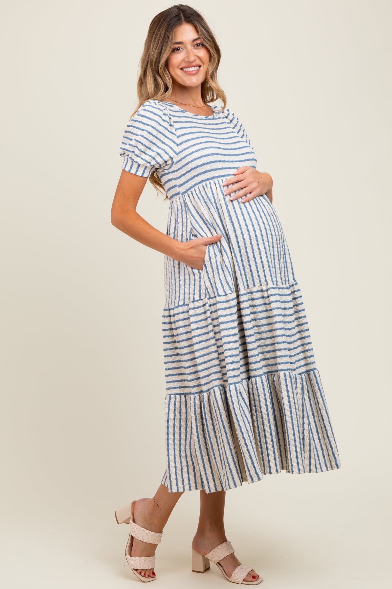 woman wearing a striped maternity dress with short sleeves and pockets, highlighting her baby bump