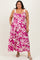 woman wearing a pink and white floral maxi dress with tie straps and pockets, smiling at the camera