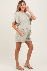 woman wearing a light green maternity short set with a relaxed fit and pockets, showing a baby bump