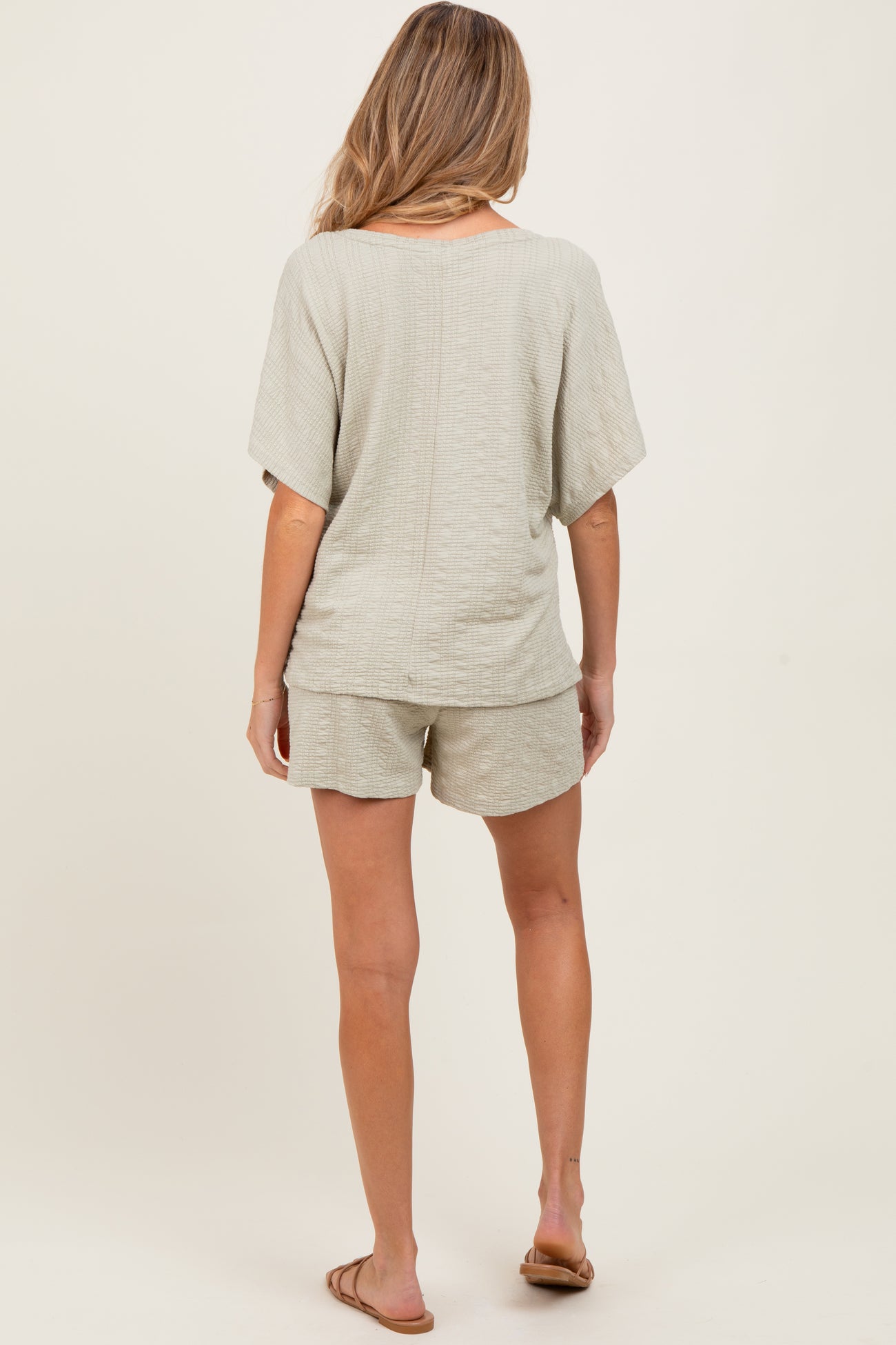 woman wearing a light gray maternity short set with a textured pattern, featuring loose-fitting shorts and a short sleeve top
