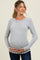 woman wearing a light gray ribbed long sleeve maternity top and holding her baby bump