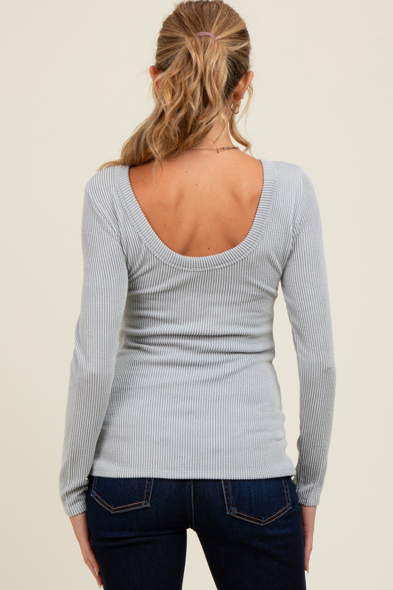 woman wearing a light gray ribbed maternity top with a scoop back and long sleeves
