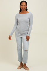 woman wearing a light gray ribbed long sleeve top and distressed light wash jeans with beige flats