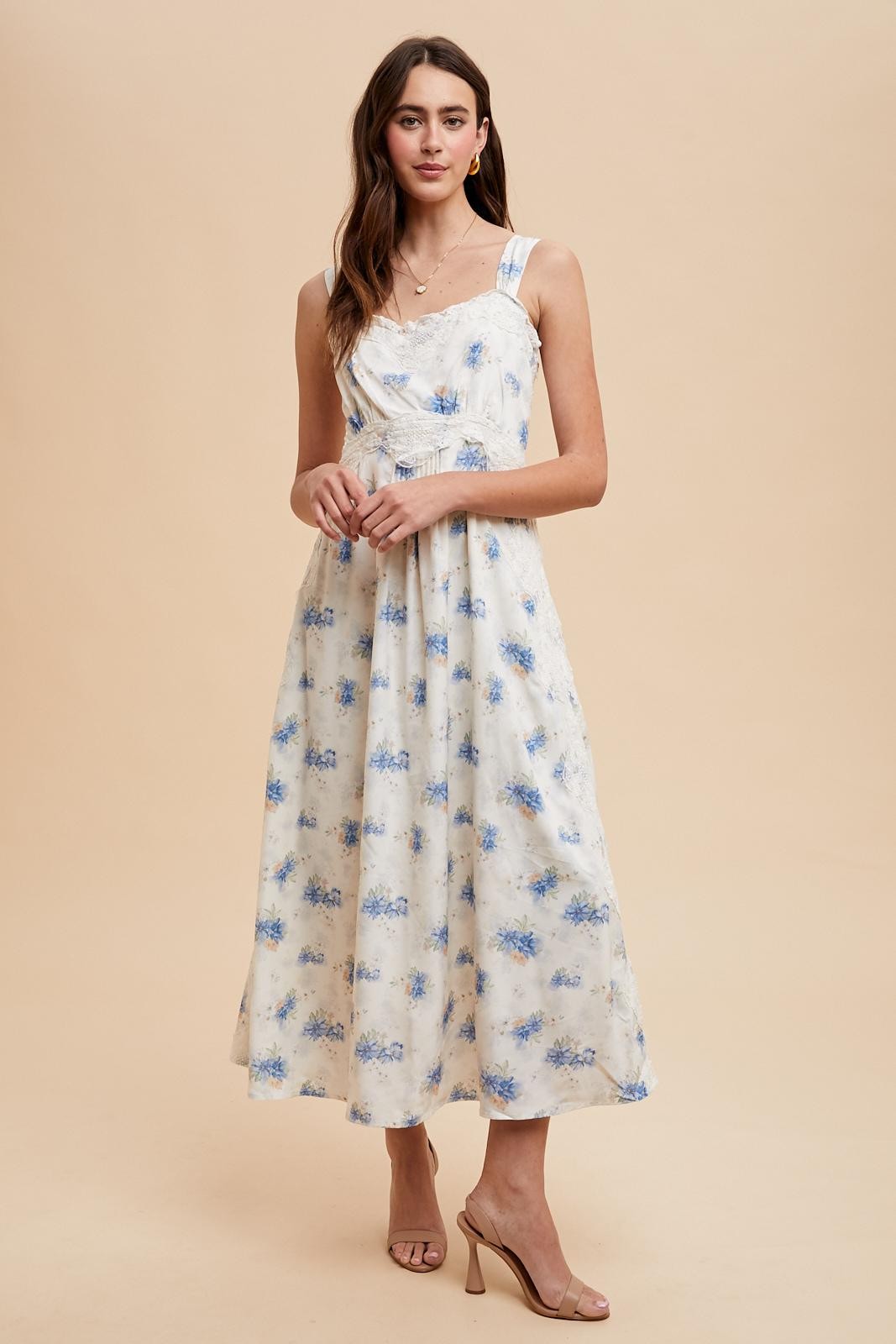 woman wearing a floral print midi dress with blue and white colors, featuring adjustable straps and a fitted bodice