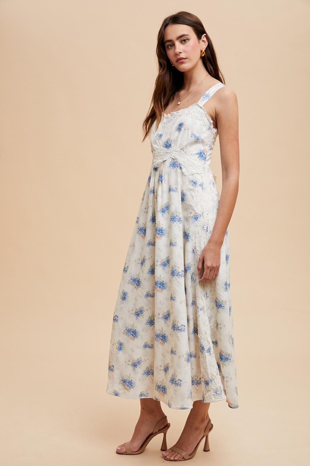 woman wearing a floral midi dress in light blue and white with a fitted bodice and flowing skirt