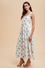 woman wearing a floral midi dress in light blue and white with a fitted bodice and flowing skirt