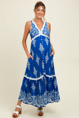 woman wearing a blue maternity maxi dress with white floral patterns and pockets, showcasing her baby bump