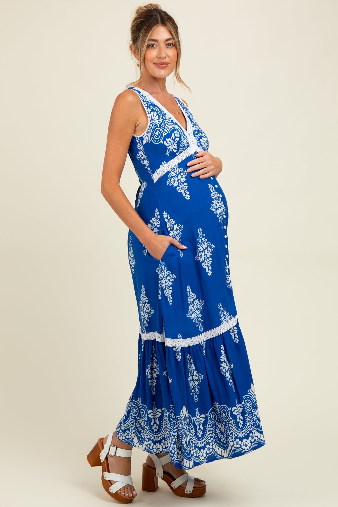 woman wearing a blue floral print maternity maxi dress and holding her baby bump