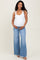 woman wearing a white maternity tank top and light blue flared maternity jeans, showing her baby bump