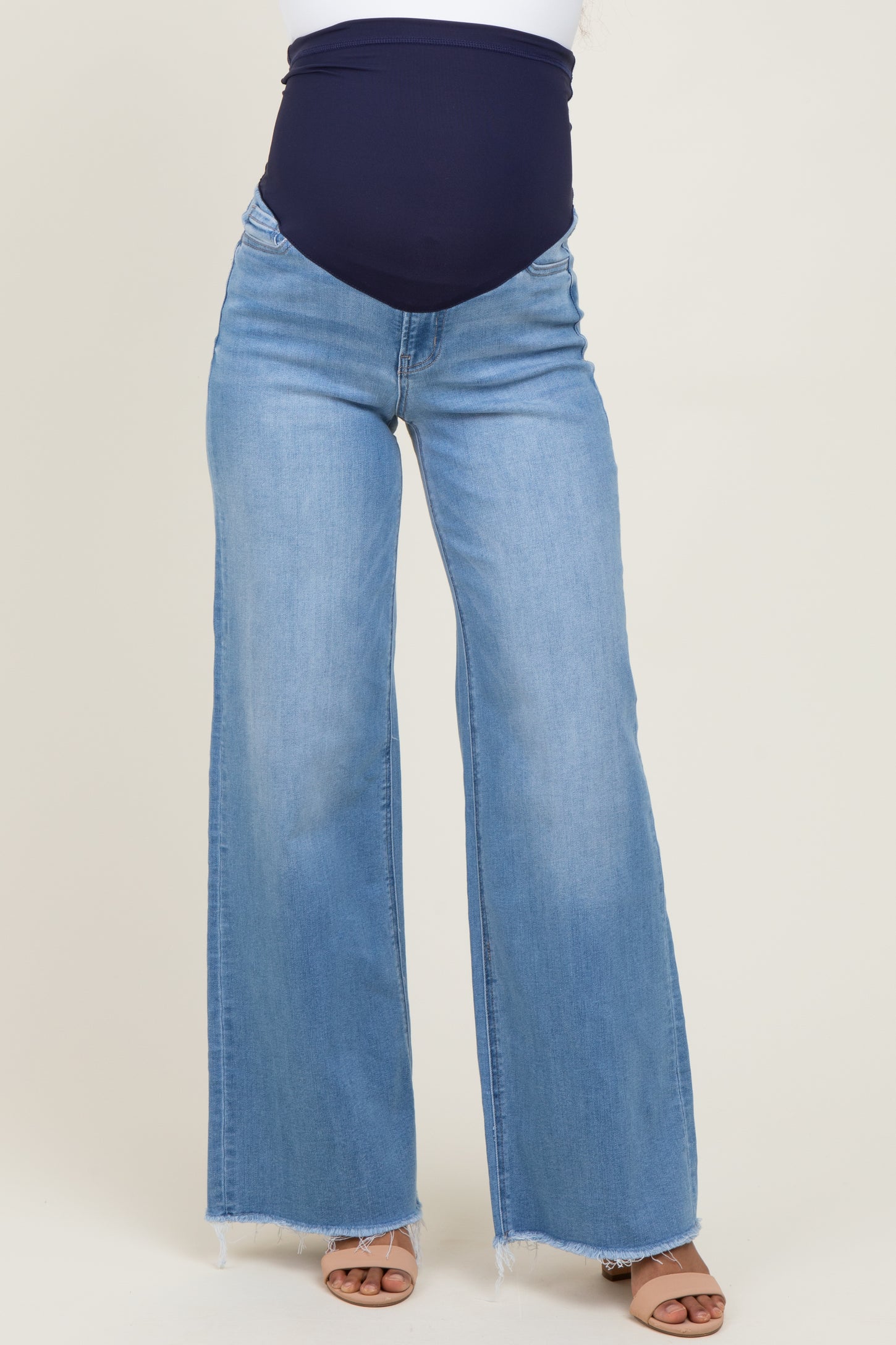 woman wearing a navy blue maternity waistband and light blue wide-leg maternity jeans